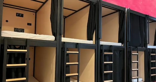 Several sleeping pods from a Brownstone Shared Living location on a pink background.